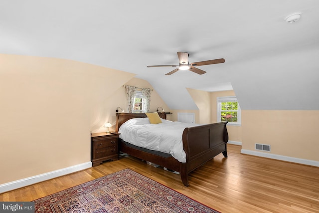 bedroom featuring baseboards, vaulted ceiling, visible vents, and multiple windows