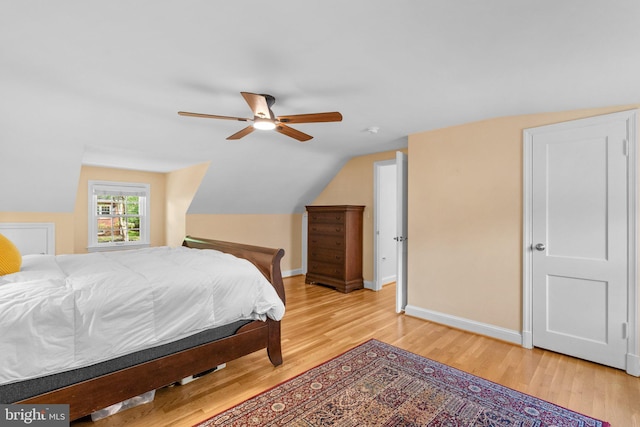 bedroom with baseboards, vaulted ceiling, a ceiling fan, and light wood-style flooring