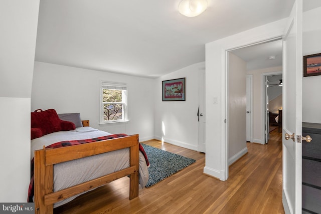 bedroom with lofted ceiling, light wood-style floors, and baseboards