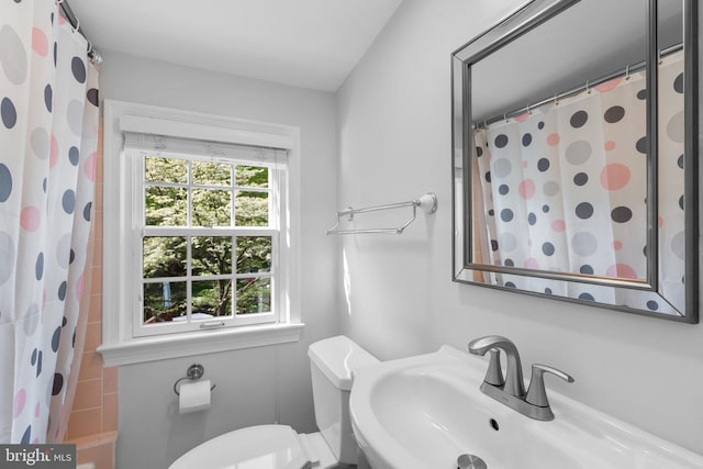 bathroom with toilet, a shower with shower curtain, and a sink