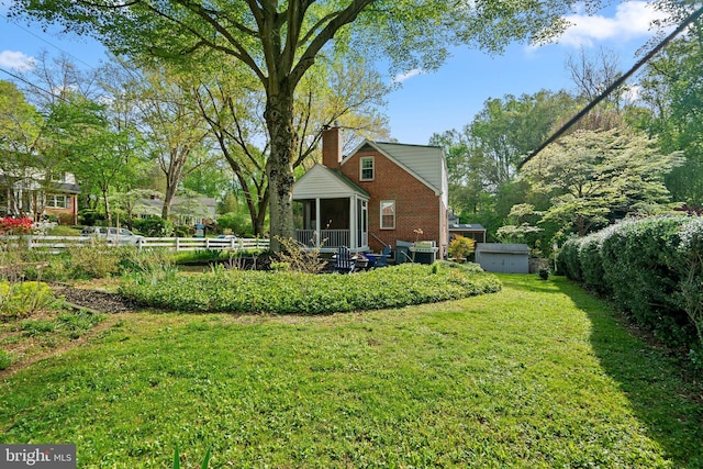 rear view of property featuring a chimney, a yard, a shed, an outbuilding, and brick siding
