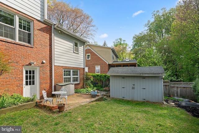 back of property featuring fence, a yard, an outbuilding, a storage unit, and brick siding