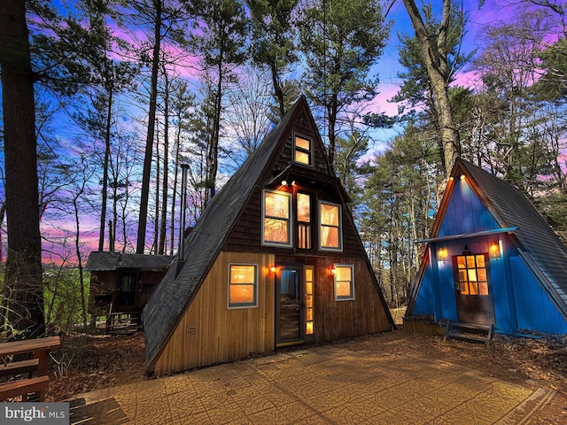 a-frame style home featuring a patio area and roof with shingles