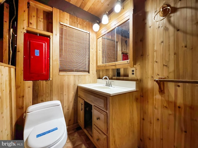 bathroom featuring toilet, wood walls, and vanity