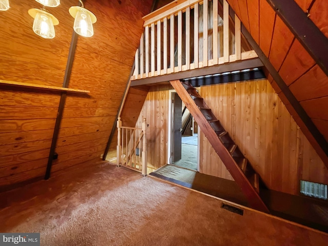 stairway with wooden walls and carpet floors