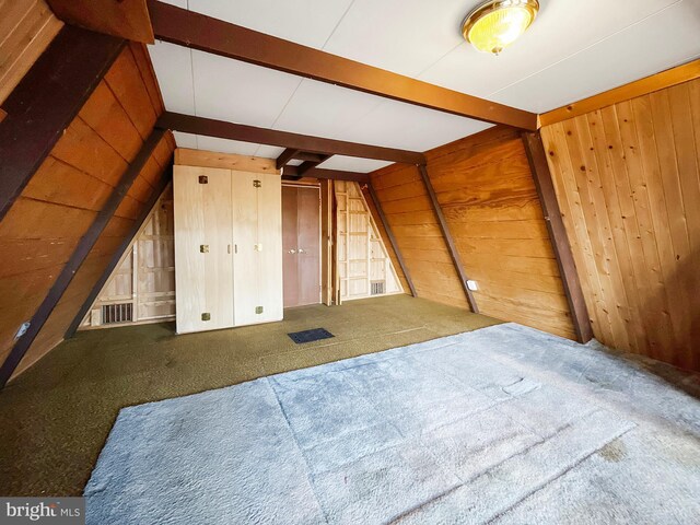 additional living space with wooden walls, beam ceiling, and carpet