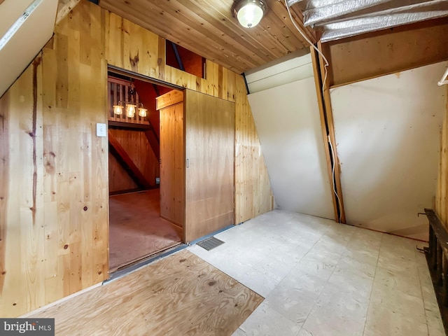 interior space with wood walls, tile patterned floors, and vaulted ceiling