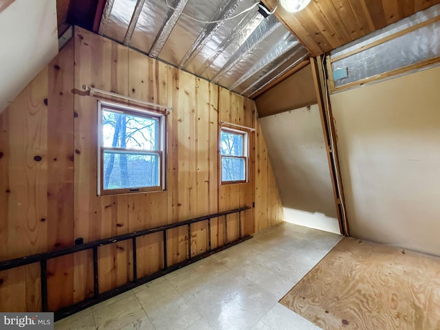 bonus room with wood walls and lofted ceiling