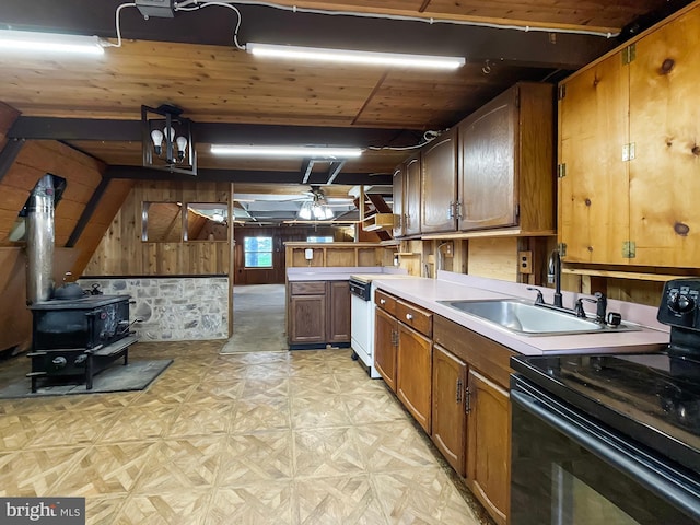 kitchen featuring a wood stove, light countertops, a sink, black range with electric cooktop, and wooden walls