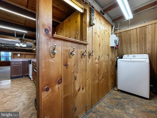 clothes washing area with wood walls, washer / dryer, and a ceiling fan