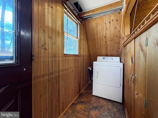 laundry room with wooden walls, washer / dryer, and laundry area
