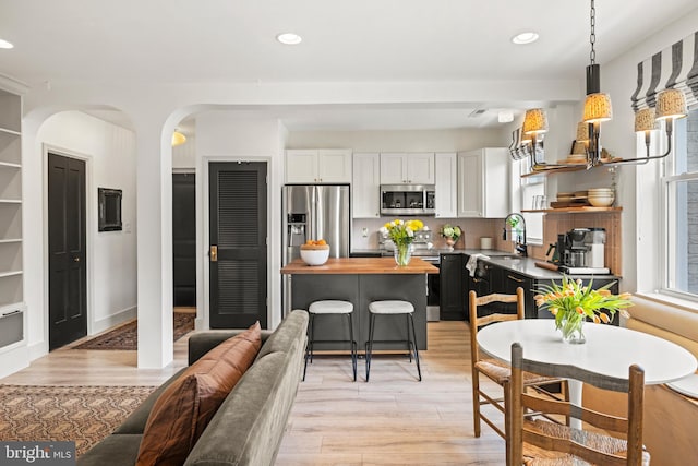 kitchen featuring a healthy amount of sunlight, appliances with stainless steel finishes, open shelves, and wood counters