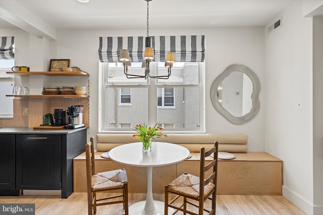 dining space featuring visible vents, light wood-style flooring, baseboards, and a chandelier