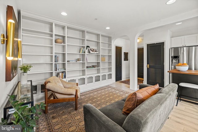 sitting room featuring light wood-style floors, arched walkways, built in features, and recessed lighting
