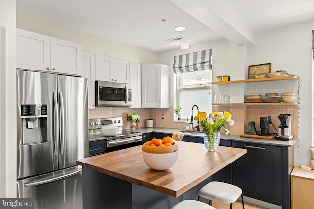 kitchen with decorative backsplash, white cabinets, stainless steel appliances, and butcher block counters