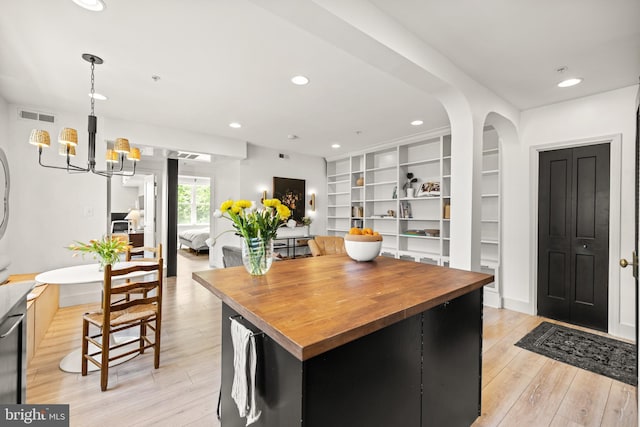 kitchen with wooden counters, visible vents, arched walkways, light wood finished floors, and a chandelier