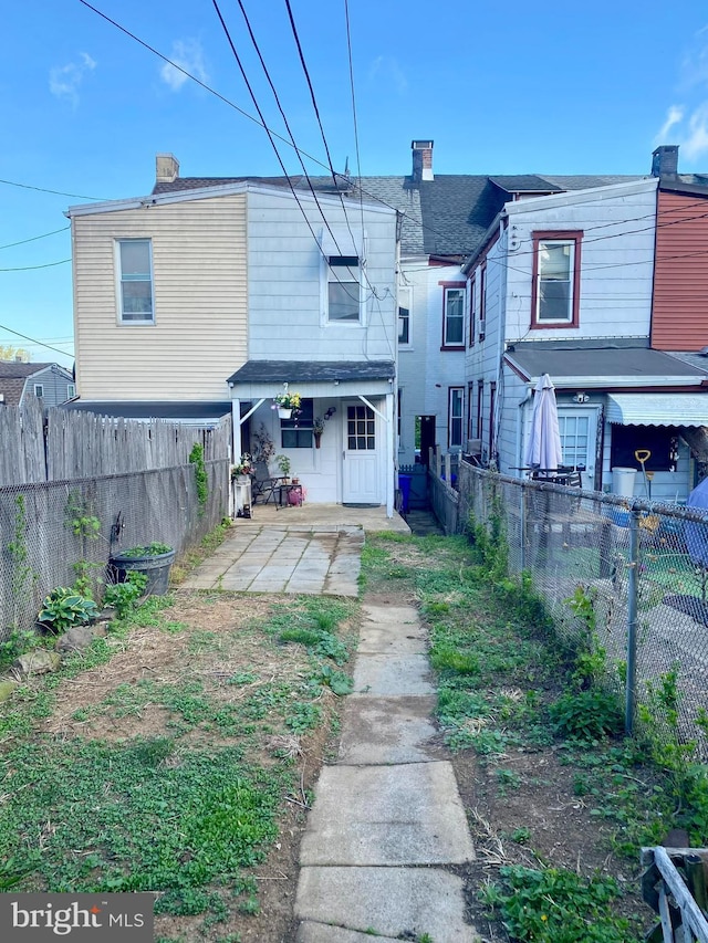 rear view of property with a fenced backyard, a patio area, and a chimney