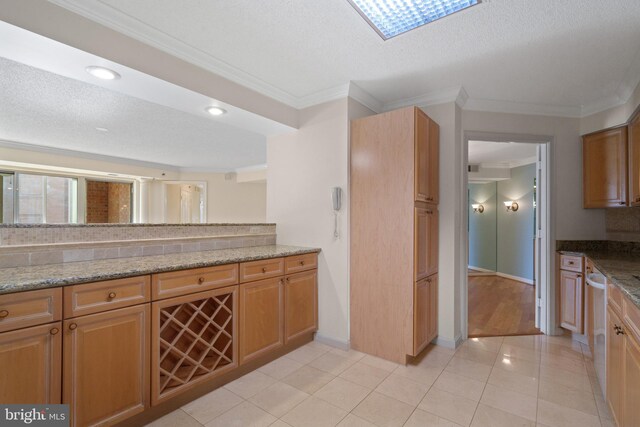kitchen with ornamental molding, stainless steel dishwasher, baseboards, light tile patterned floors, and light stone countertops