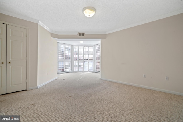 empty room with carpet floors, crown molding, baseboards, and a textured ceiling