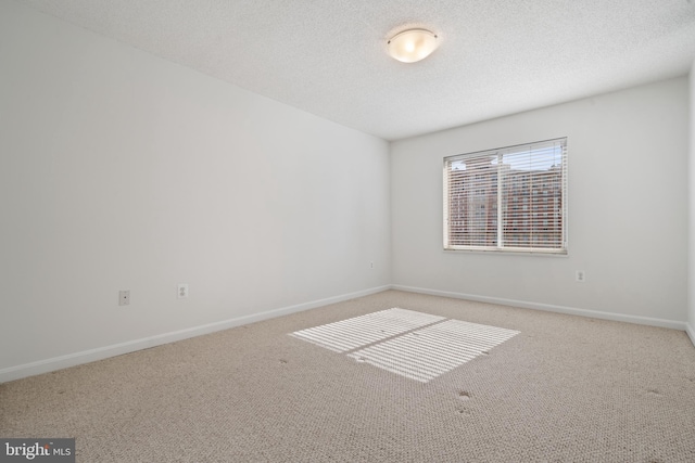 empty room with carpet, baseboards, and a textured ceiling