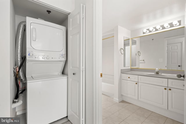 clothes washing area with stacked washer / drying machine and light tile patterned floors