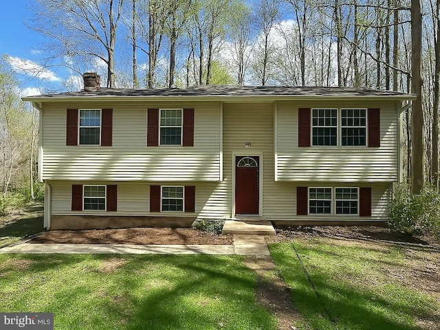 split foyer home featuring a front yard and a chimney