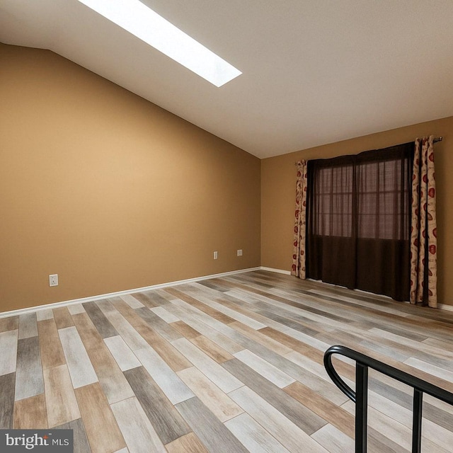 unfurnished room featuring light wood-style floors and vaulted ceiling with skylight