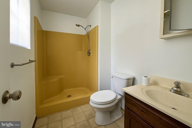 bathroom featuring toilet, vanity, tile patterned floors, and a shower