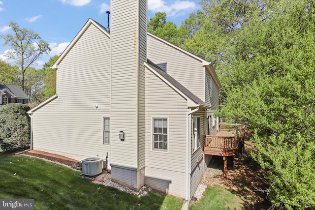 view of side of property featuring a wooden deck, a yard, central AC, and a chimney