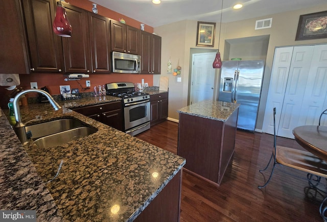 kitchen with visible vents, a sink, dark wood-style flooring, appliances with stainless steel finishes, and a kitchen island