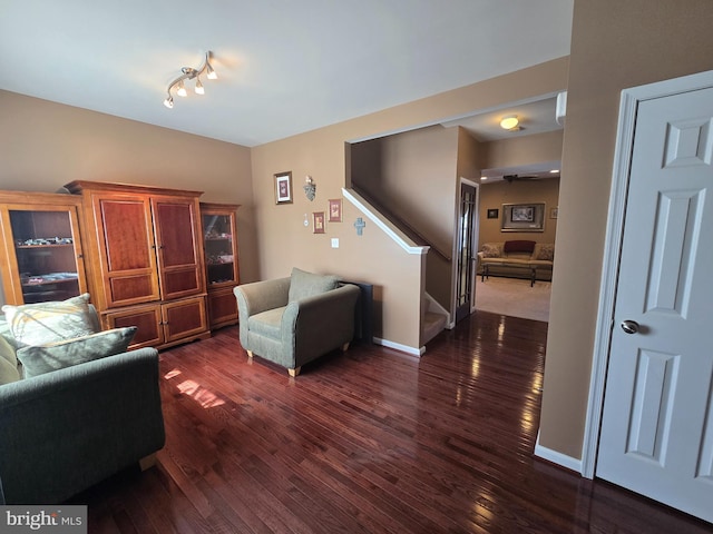 living area with baseboards, dark wood finished floors, and stairs