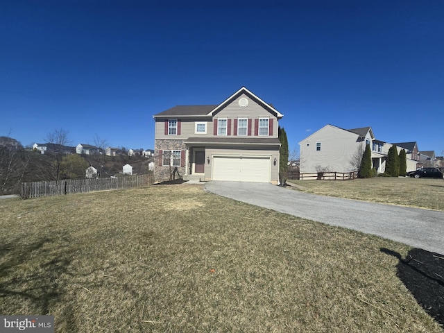 traditional-style home featuring a front lawn, fence, a garage, and driveway