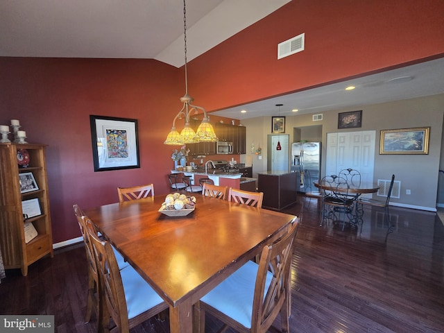 dining space with dark wood-style flooring, visible vents, and vaulted ceiling
