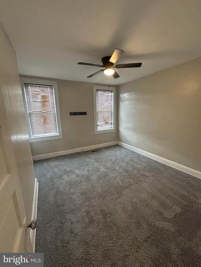 carpeted spare room featuring baseboards and a ceiling fan