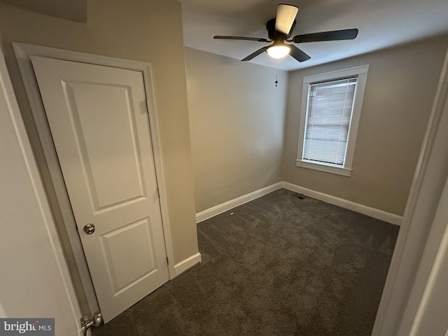 spare room featuring dark colored carpet, baseboards, and ceiling fan