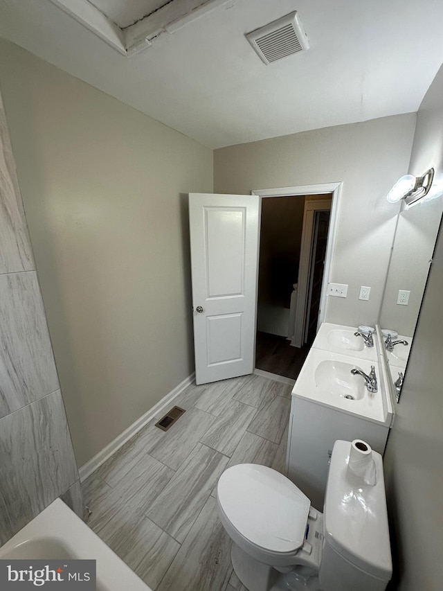 bathroom with double vanity, toilet, baseboards, and visible vents
