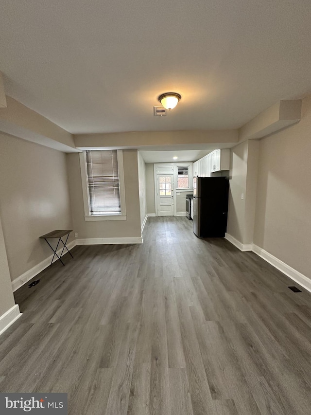unfurnished living room with baseboards, dark wood finished floors, and visible vents