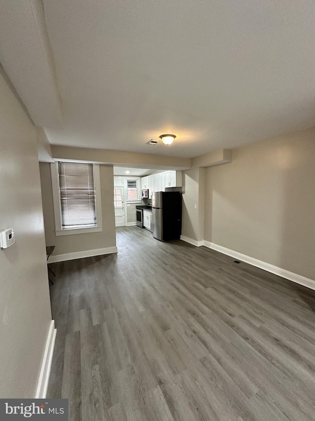 unfurnished living room featuring baseboards and dark wood-style floors