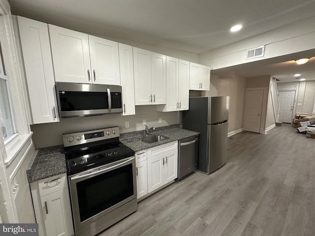 kitchen featuring a sink, appliances with stainless steel finishes, white cabinetry, and visible vents