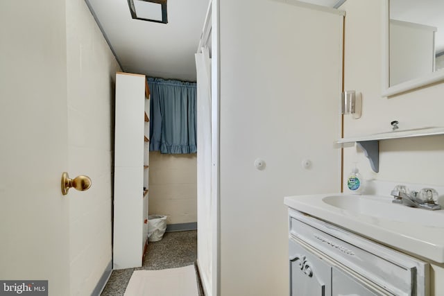 bathroom featuring concrete block wall and vanity