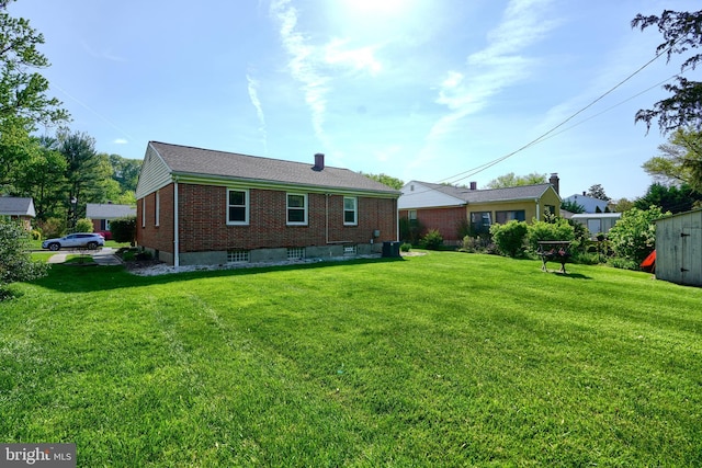 back of house with brick siding and a yard