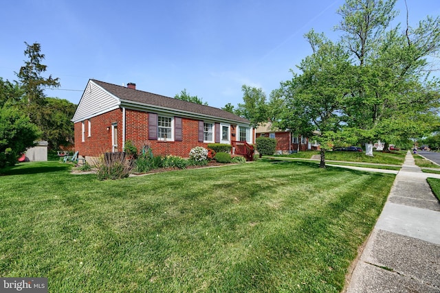view of front of property featuring brick siding, a chimney, and a front yard