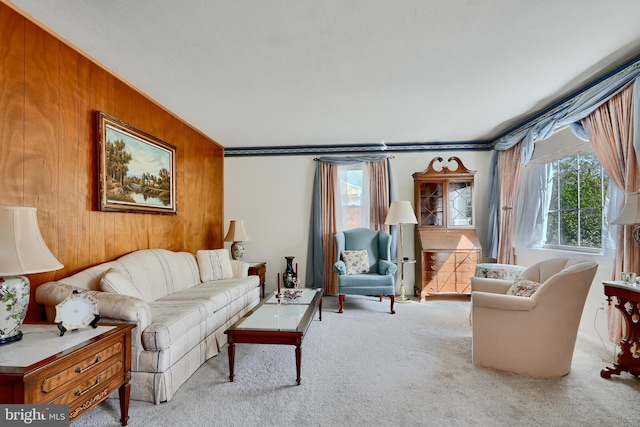 carpeted living room featuring wood walls