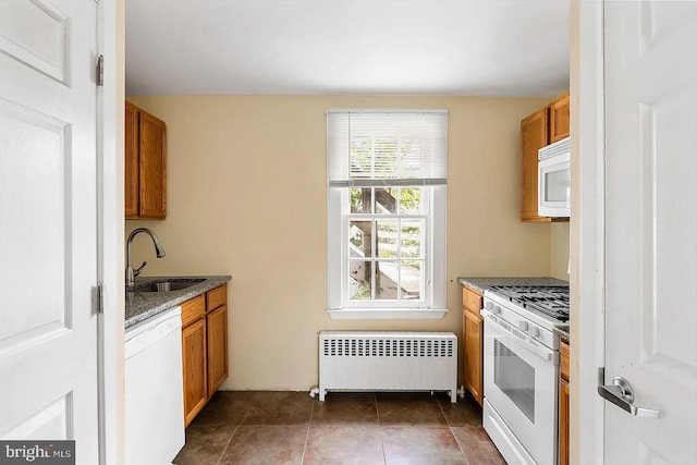 kitchen featuring a sink, white appliances, radiator, and brown cabinets