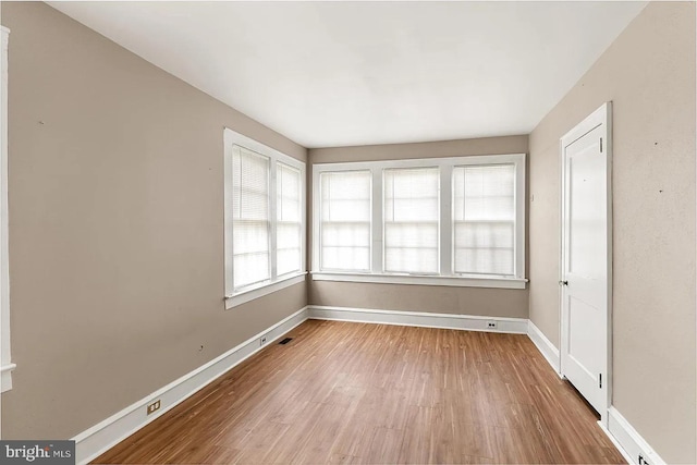 empty room with visible vents, baseboards, and wood finished floors