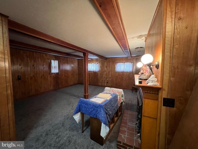 carpeted bedroom featuring wooden walls and beam ceiling