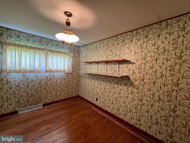 empty room featuring wallpapered walls, wood finished floors, and baseboards