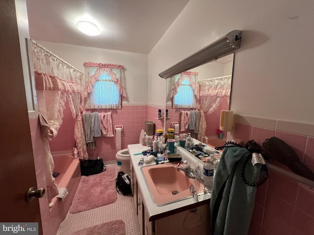 full bath with a wainscoted wall, toilet, tile walls, tile patterned flooring, and vanity