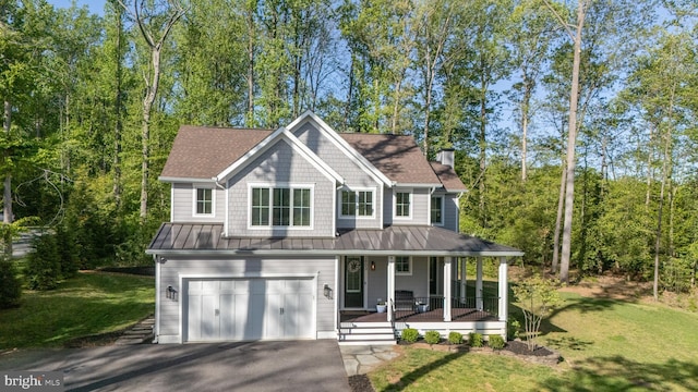 view of front facade with a porch, a garage, aphalt driveway, and a standing seam roof