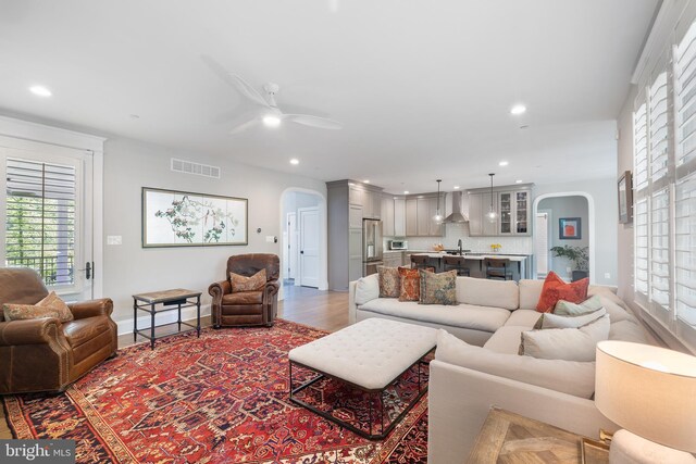 living room with visible vents, arched walkways, plenty of natural light, and ceiling fan